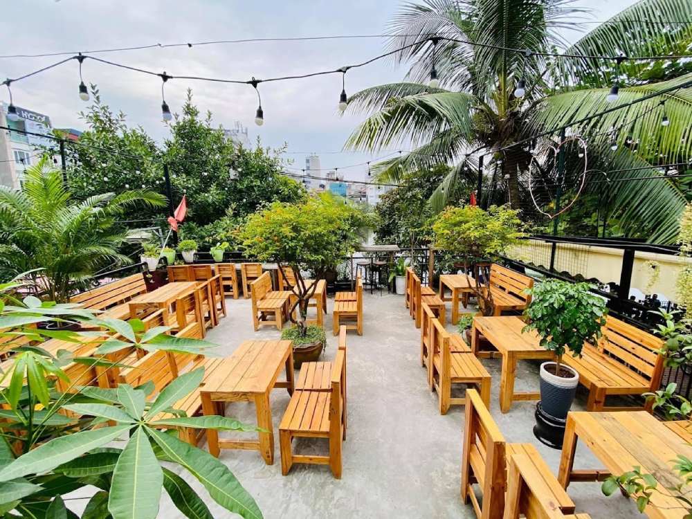 Khám Phá Garden Coffee Đội Cấn: Không Gian Yên Tĩnh Giữa Lòng Thủ Đô 7 Khu vườn ngoài trời với bàn ghế gỗ và cây xanh, trang trí đèn treo tạo không gian thoáng đãng và thư giãn.