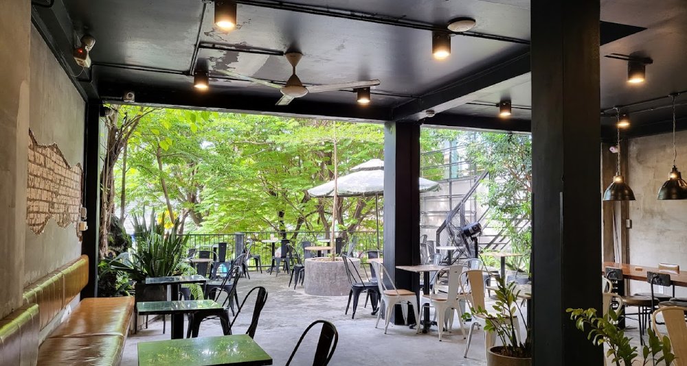 Khám Phá 8+ Quán Cafe Đêm Sài Gòn Đẹp Lung Linh Bạn Không Thể Bỏ Lỡ 11 Quán cà phê rộng rãi, thiết kế mở với bàn ghế đơn giản, cây xanh xung quanh và ánh sáng tự nhiên.
