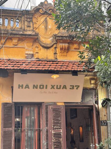 go-and-share-cafe-co-ha-noi-10 Mặt tiền quán cà phê với biển hiệu "Hà Nội Xưa 37", tường sơn vàng, cửa gỗ và mái ngói đỏ.