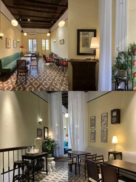 Qu&aacute;n c&agrave; ph&ecirc; với nội thất cổ điển, b&agrave;n ghế gỗ, s&agrave;n gạch hoa, đ&egrave;n treo, v&agrave; c&acirc;y xanh trang tr&iacute;.