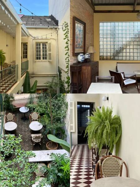 Qu&aacute;n c&agrave; ph&ecirc; phong c&aacute;ch cổ điển với b&agrave;n ghế gỗ, c&acirc;y xanh, v&agrave; &aacute;nh s&aacute;ng tự nhi&ecirc;n từ cửa sổ lớn.