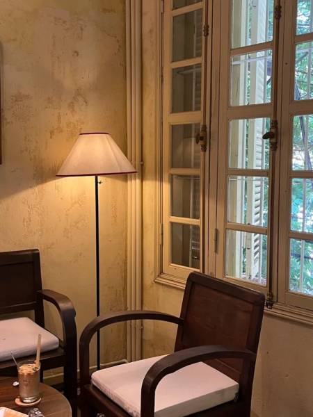 G&oacute;c ph&ograve;ng với đ&egrave;n đứng, hai ghế gỗ c&oacute; nệm trắng, cửa sổ k&iacute;nh lớn b&ecirc;n cạnh, tường m&agrave;u v&agrave;ng nhạt.