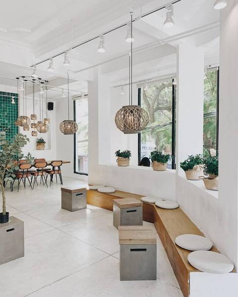 Qu&aacute;n c&agrave; ph&ecirc; hiện đại, nội thất tối giản với ghế gỗ, b&agrave;n d&agrave;i, c&acirc;y xanh v&agrave; đ&egrave;n treo trang tr&iacute;, tạo kh&ocirc;ng gian tho&aacute;ng đ&atilde;ng.