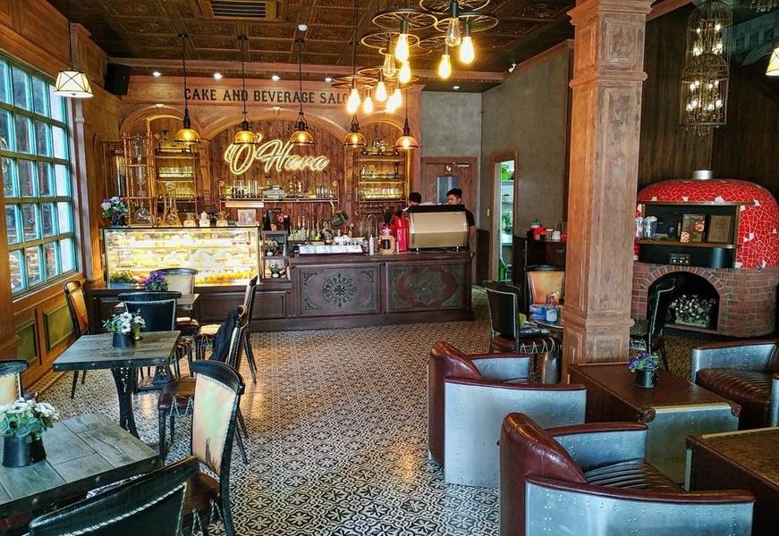 Qu&aacute;n c&agrave; ph&ecirc; ấm c&uacute;ng với b&agrave;n ghế b&agrave;y tr&iacute;, quầy pha chế v&agrave; tủ b&aacute;nh, trang tr&iacute; đ&egrave;n v&agrave; l&ograve; nướng gạch đỏ.