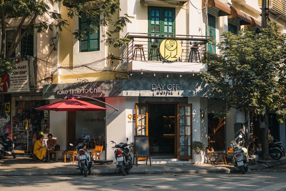 Khám Phá Top 10+ Quán Cafe Quán Thánh Lý Tưởng cho Hẹn Hò, Làm Việc và Thư Giãn 13 Quán cà phê nhỏ với biển hiệu "Day Off Coffee", có ô đỏ và xe máy đỗ phía trước trên vỉa hè.