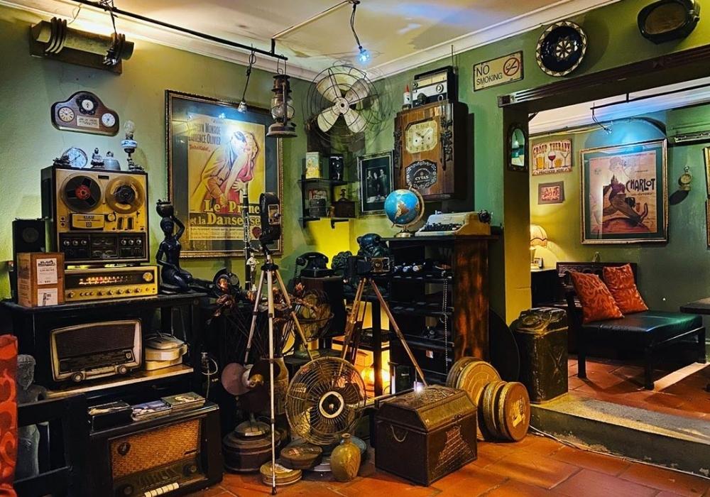 Khám Phá Top Quán Cafe Đẹp Ở Liễu Giai: Đồ Uống Ngon, Không Gian Thư Giãn 10 Căn phòng cổ điển với đồ vật trang trí hoài cổ như máy quay, đồng hồ, và áp phích phim trên tường.