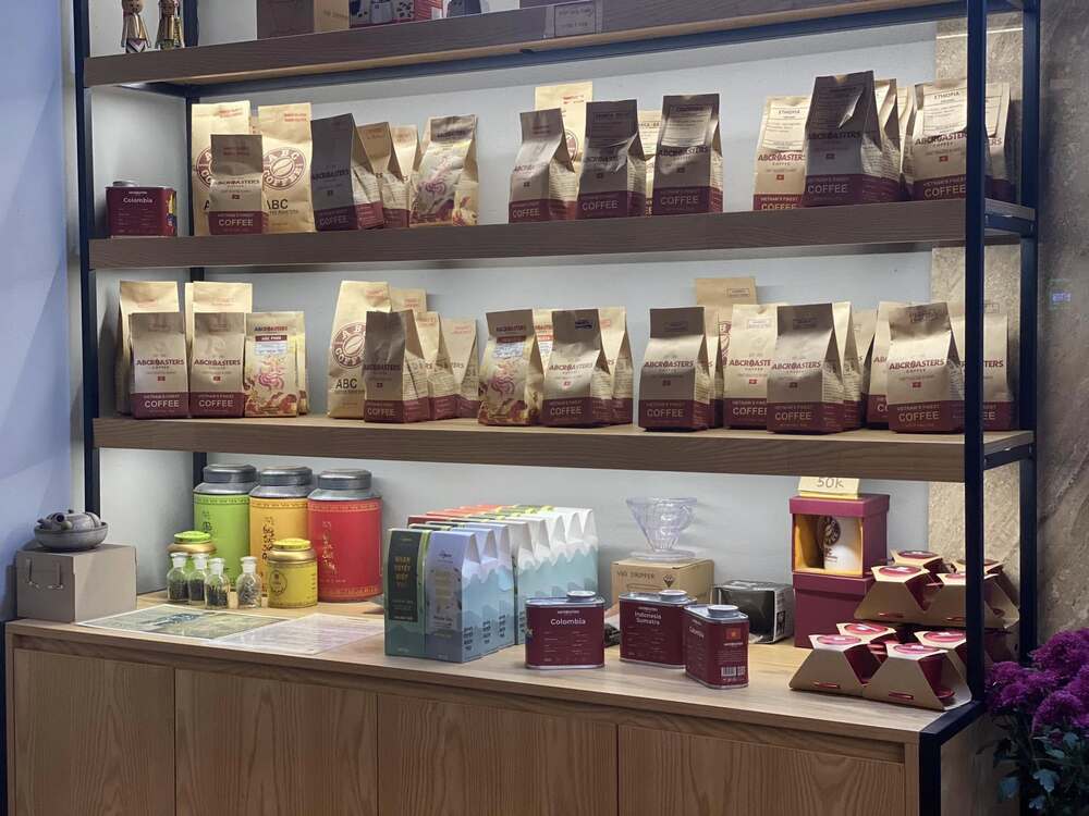 Khám Phá 10+ Quán Cafe Đẹp Ở Đặng Văn Ngữ: Đồ Uống Ngon, Giá Cả Hấp Dẫn 18 Kệ trưng bày nhiều loại sản phẩm cà phê và trà, bao gồm túi, hộp và lon, sắp xếp gọn gàng trên các ngăn kệ.
