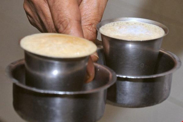 2 Hai cốc kim loại chứa đầy đồ uống có bọt, được giữ bằng tay.