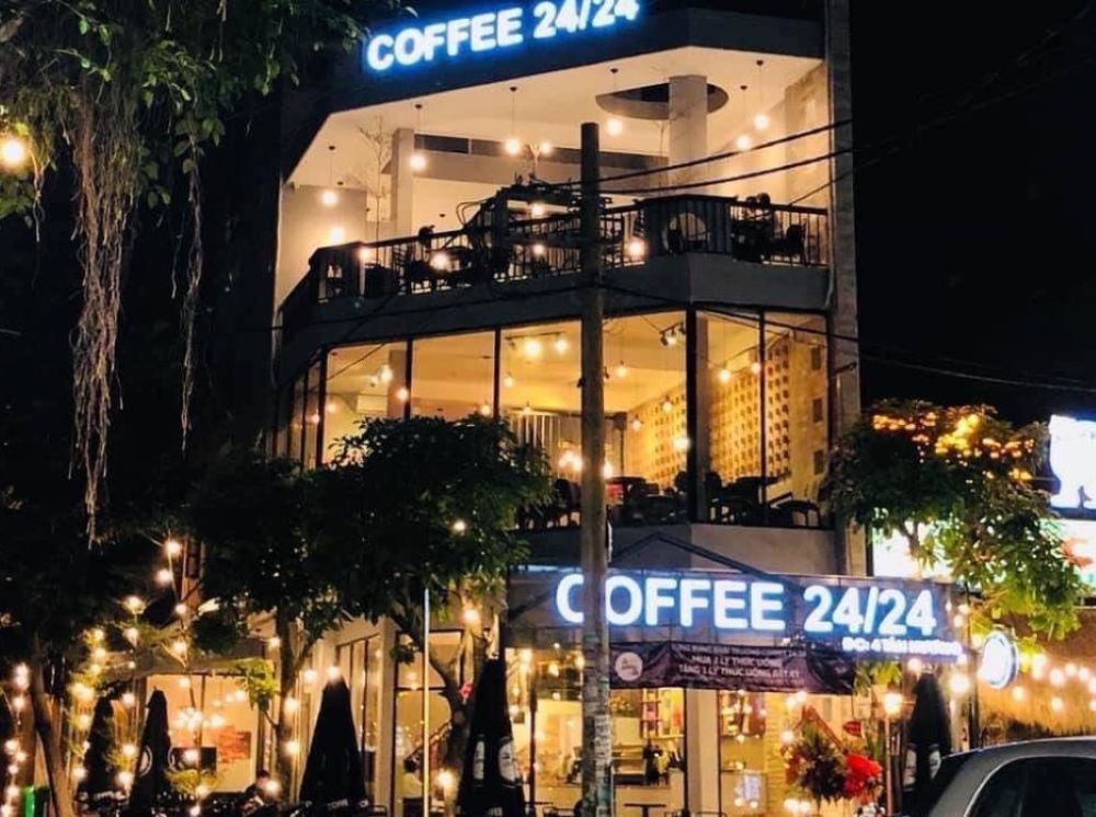 Khám Phá 4 Quán Cafe 24h Ở Bình Thạnh Hoàn Hảo Cho Làm Việc Và Thư Giãn 6 Quán cà phê ba tầng sáng đèn vào ban đêm, có bảng hiệu "COFFEE 24/24" và trang trí ánh sáng lung linh.