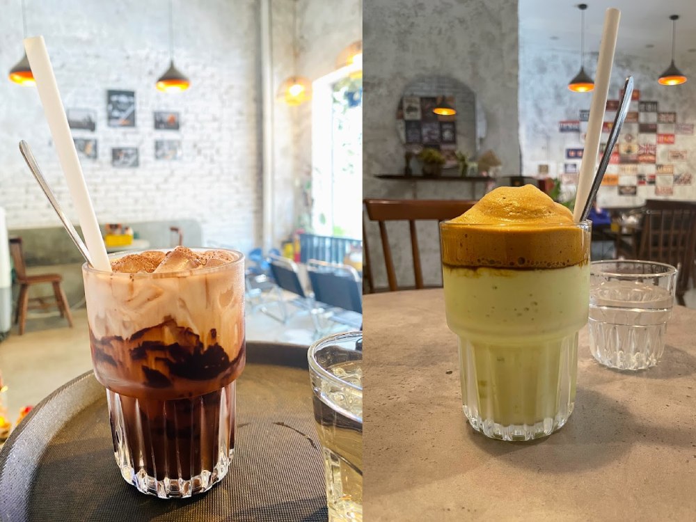 Khám Phá 11 Quán Cafe Đội Cấn Tuyệt Vời Cho Thư Giãn Và Làm Việc 19 Hai ly đồ uống trang trí đẹp mắt, một ly với kem chocolate, ly kia có lớp bọt cà phê, trên bàn quán cà phê.