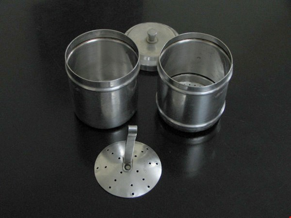 31 Bộ phin pha cà phê bằng inox gồm hai phin và nắp, đặt trên bề mặt tối màu.