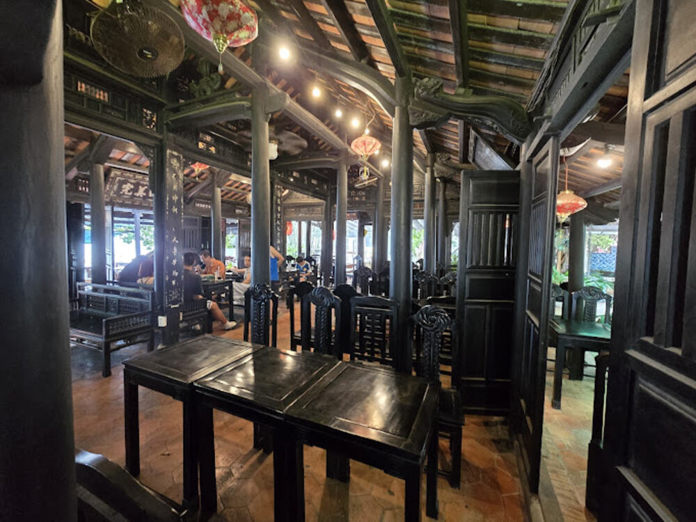 Top 5 Quán Cafe Cá Koi Đẹp Không Thể Bỏ Qua Tại Quy Nhơn 7 Nội thất nhà hàng truyền thống với bàn ghế gỗ tối màu, đèn lồng treo và mái ngói đặc trưng.