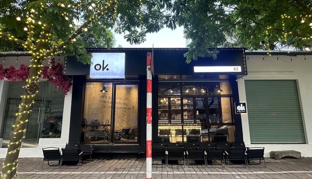 Khám Phá 15 Quán Cafe Hấp Dẫn Trên Đường Nguyễn Thị Định 5 Mặt tiền quán cà phê hiện đại với bảng hiệu sáng, cây trang trí đèn và ghế ngồi ngoài trời, không gian thoáng đãng.
