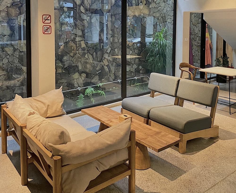 Khám Phá 15+ Quán Cafe View Đẹp, Đồ Uống Ngon Tại Hoàng Cầu 12 Phòng khách hiện đại với ghế sofa gỗ, bàn gỗ, cửa sổ kính lớn nhìn ra ngoài, cây xanh trang trí.