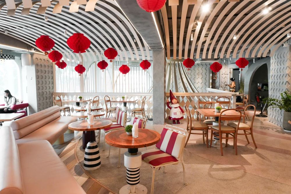 Khám Phá Top 10 Quán Cafe Giảng Võ Hấp Dẫn Nhất Tại Hà Nội 6 Quán cà phê với thiết kế hiện đại, trang trí đèn lồng đỏ, bàn ghế gỗ và ghế sofa sáng màu, không gian rộng rãi.