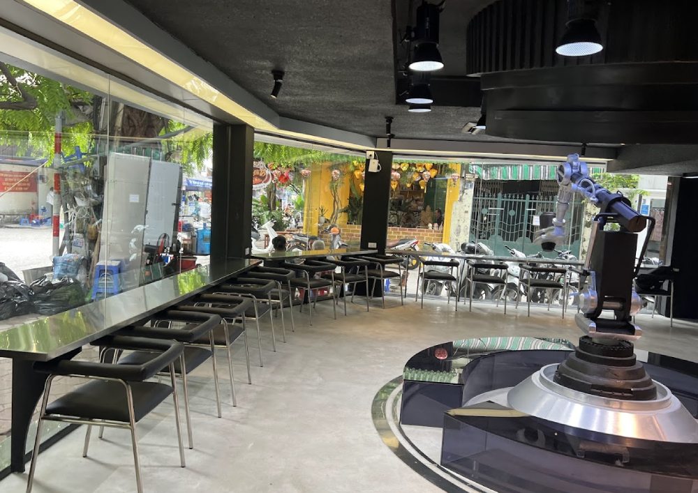 Khám Phá 12+ Quán Cafe Đẹp Ở Tây Sơn Với Đồ Uống Ngon 18 Không gian quán cà phê hiện đại với bàn ghế sắp xếp gọn gàng và một cánh tay robot bên trong.