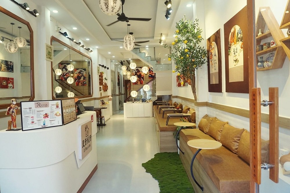 Khám Phá 12+ Quán Cafe Đẹp Hút Triệu View Tại TPHCM Năm 2025 16 Quán cà phê với nội thất sáng, tranh tường nghệ thuật, bàn ghế gỗ và đèn lồng trang trí, tạo không gian ấm cúng.