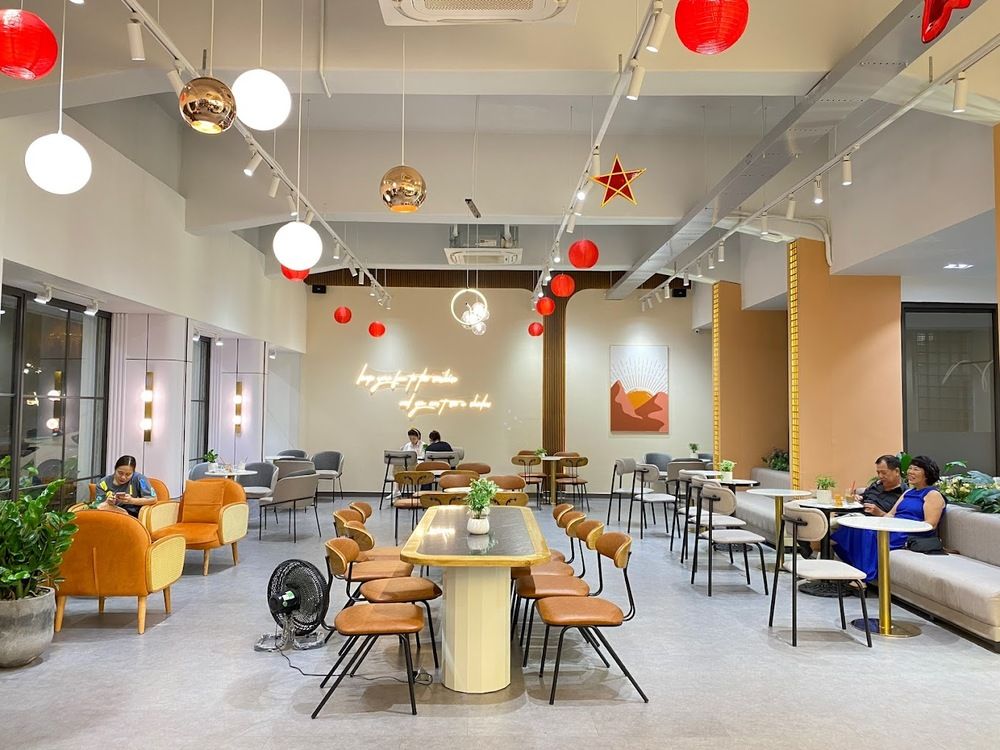 Khám Phá Top 10 Quán Cafe Giảng Võ Hấp Dẫn Nhất Tại Hà Nội 9 Quán cà phê với nội thất hiện đại, ghế sofa và bàn gỗ, trang trí bằng đèn lồng đỏ và cây xanh.