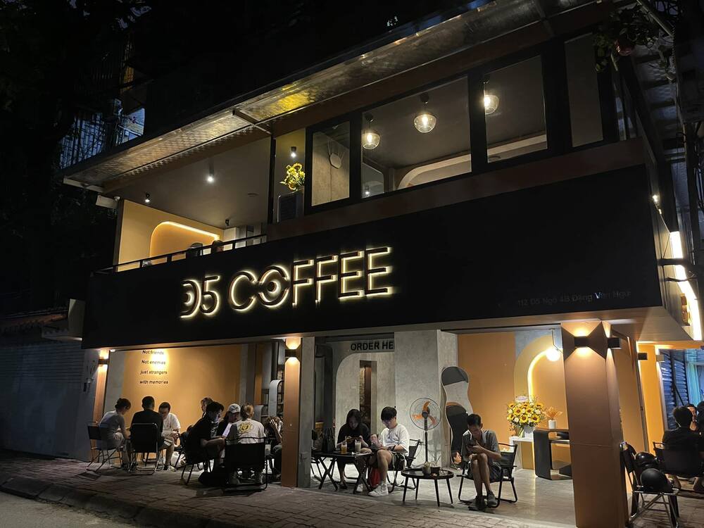 Khám Phá 10+ Quán Cafe Đẹp Ở Đặng Văn Ngữ: Đồ Uống Ngon, Giá Cả Hấp Dẫn 5 Quán cà phê hai tầng vào buổi tối, có khách ngồi bên ngoài, đèn sáng tạo không gian ấm cúng.
