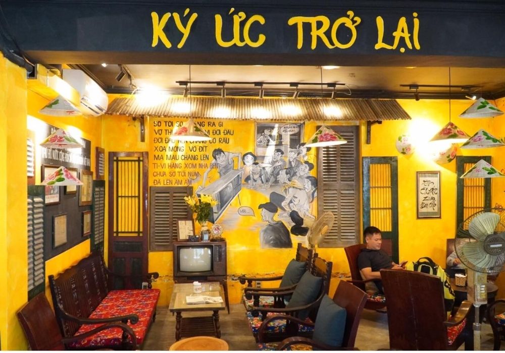 Khám Phá Top Quán Cafe Đẹp Ở Liễu Giai: Đồ Uống Ngon, Không Gian Thư Giãn 3 Quán cà phê trang trí theo phong cách hoài cổ, với tường vàng, tranh vẽ, và nội thất gỗ.
