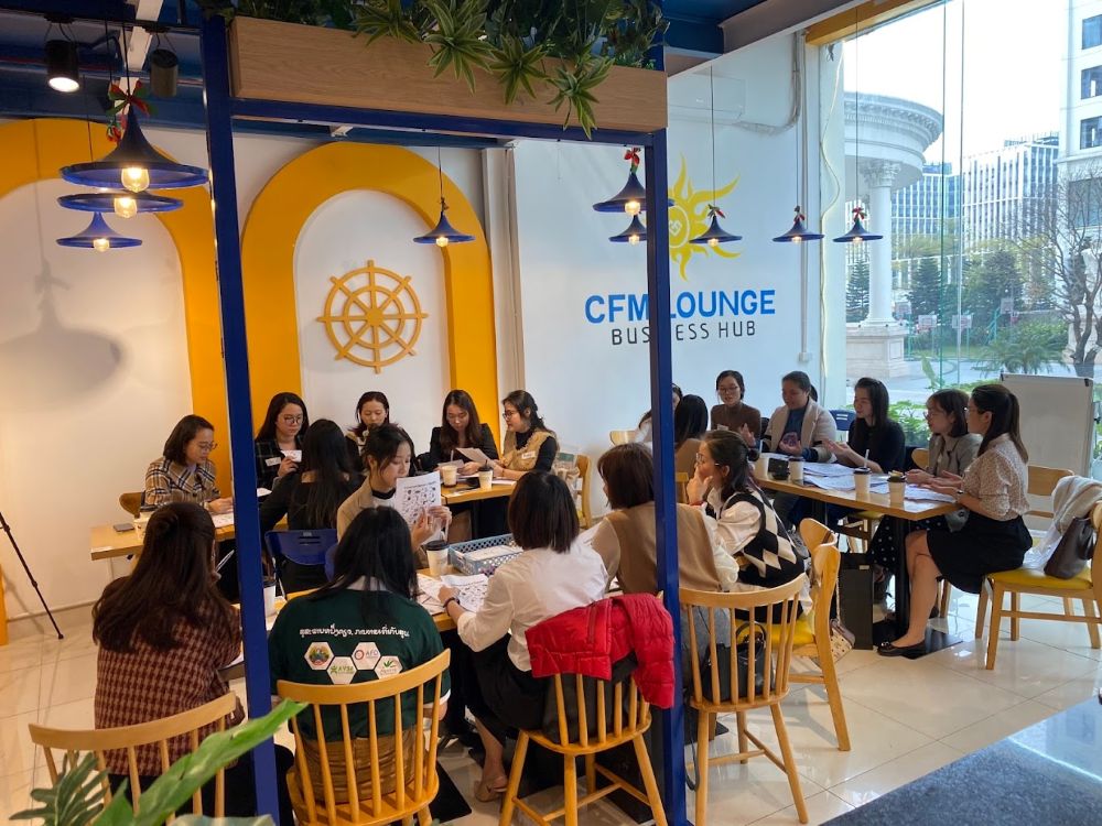 7 Quán Cafe View Đẹp Phạm Văn Đồng Không Thể Bỏ Qua 12 Một nhóm người đang ngồi xung quanh bàn trong một không gian làm việc chung, thảo luận và trao đổi tài liệu.