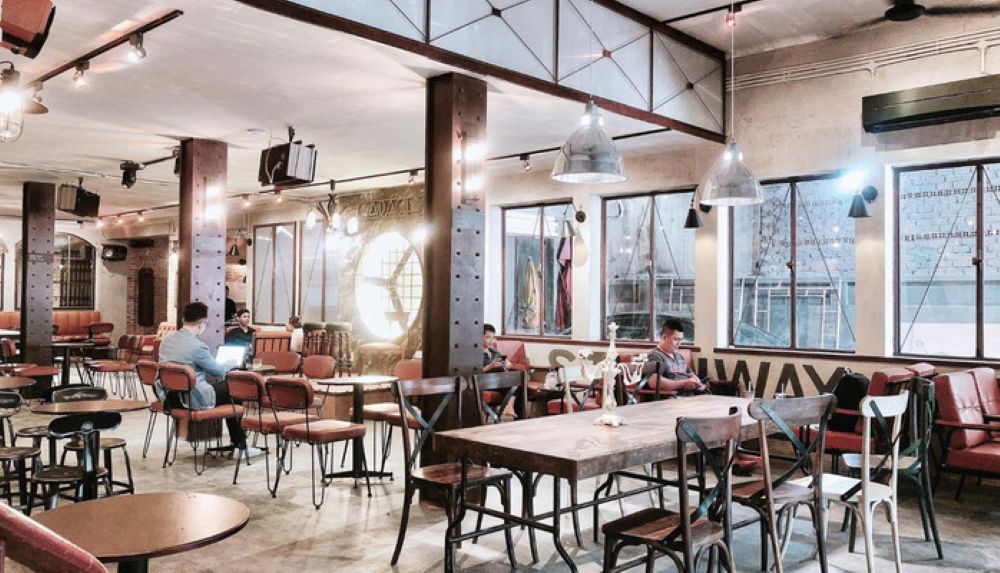 Khám Phá 4 Quán Cafe 24h Ở Bình Thạnh Hoàn Hảo Cho Làm Việc Và Thư Giãn 7 Quán cà phê rộng rãi với bàn ghế gỗ, ánh sáng ấm áp, cửa sổ lớn và vài người đang ngồi thư giãn.