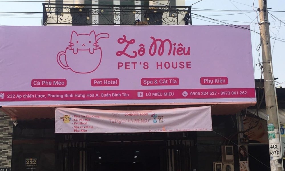 Khám Phá Quán Cafe Mèo Quận 1: Điểm Đến Lý Tưởng Cho Người Yêu Thú Cưng 9 Biển hiệu màu hồng của một cửa hàng thú cưng, có hình mèo trong tách và thông tin liên hệ bên dưới.