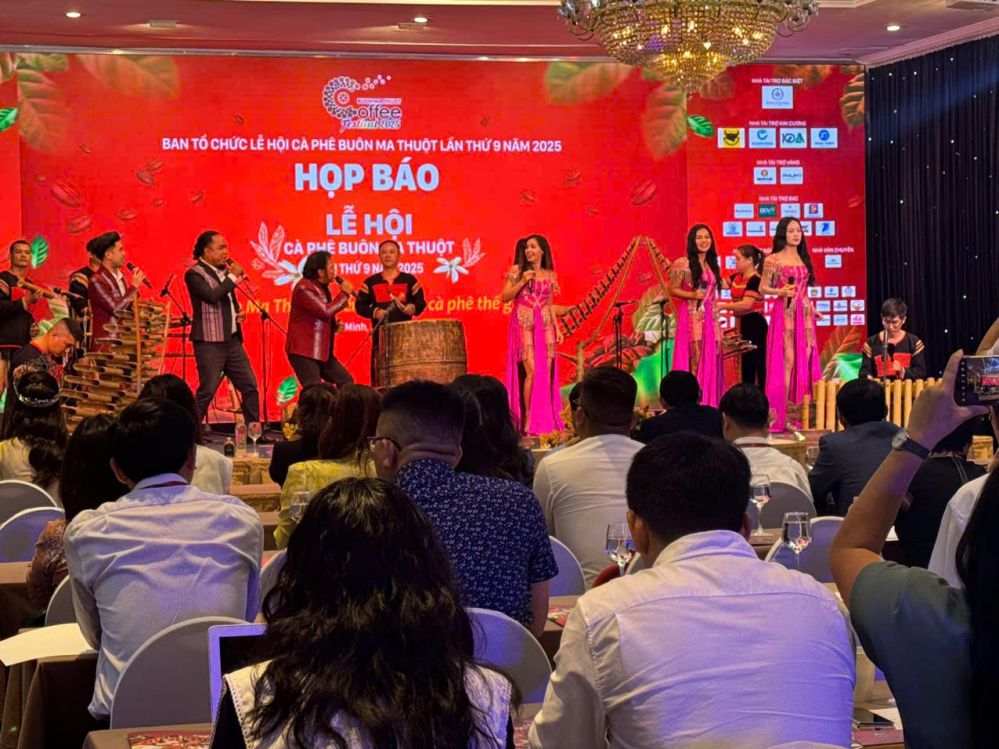 Khám Phá Lễ Hội Cà Phê Buôn Ma Thuột: Nơi Tinh Hoa Cà Phê Tụ Hội 4 Buổi họp báo với nhóm người biểu diễn trên sân khấu, khán giả ngồi theo dõi trong khán phòng trang trí rực rỡ.