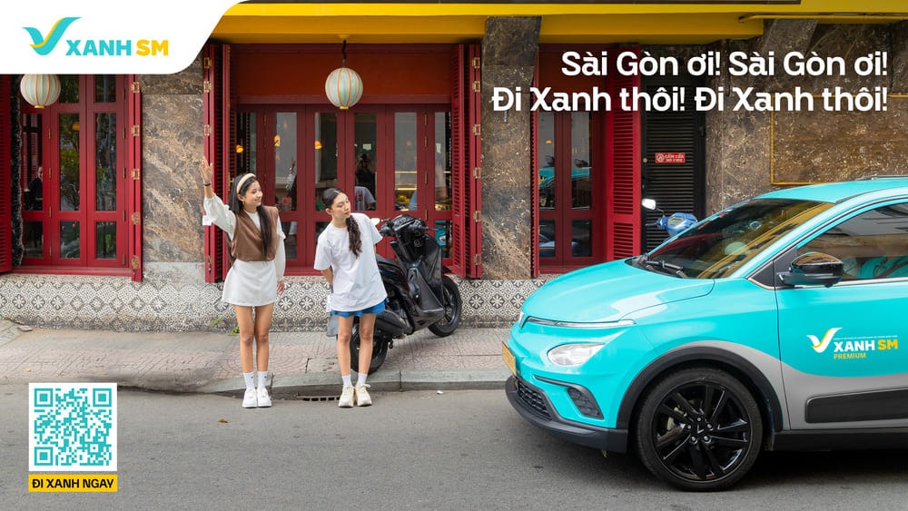 Hai người đứng bên lề đường vẫy tay gọi xe ô tô màu xanh biển của dịch vụ Xanh SM.