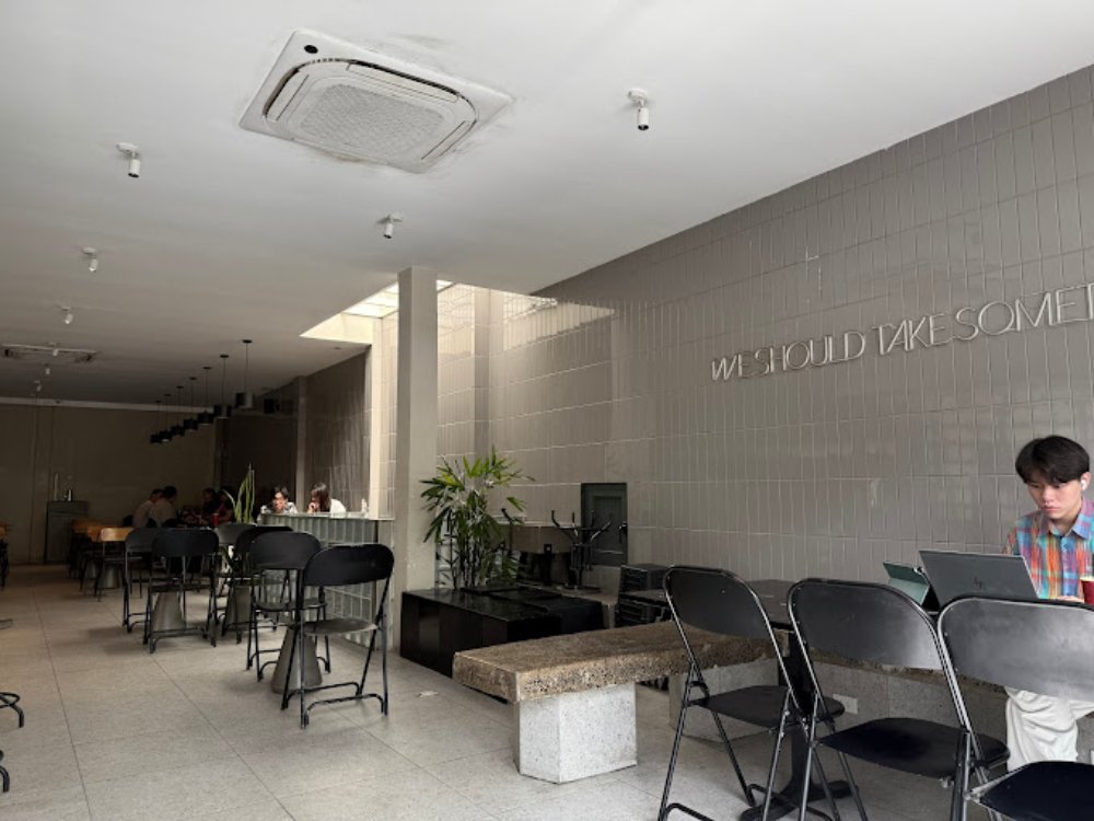 Khám Phá Top 6 Quán Cafe Mở Cửa 24h Tại Quận 3 Cho Người Yêu Thích Cú Đêm 10 Quán cà phê không gian mở, bàn ghế xếp gọn gàng, có người ngồi làm việc với laptop, ánh sáng tự nhiên.