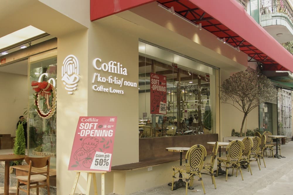 Khám Phá Top 10+ Quán Cafe Quán Thánh Lý Tưởng cho Hẹn Hò, Làm Việc và Thư Giãn 15 Quán cà phê với biển hiệu "Coffilia", có bàn ghế ngoài trời và bảng thông báo khai trương giảm giá 50%.