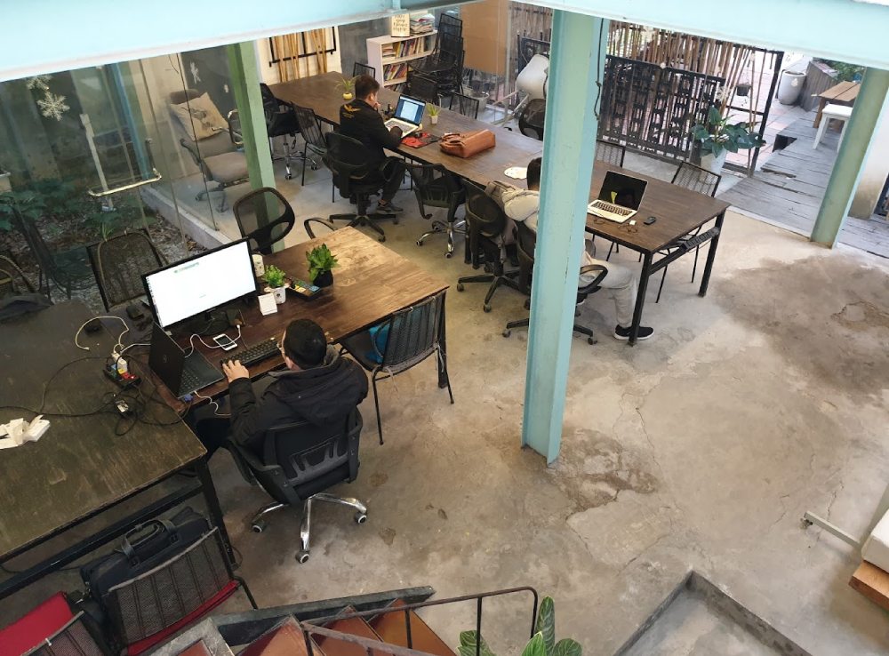Khám Phá 11 Quán Cafe Sách Độc Đáo Tại Cầu Giấy Hút Hồn Độc Giả 17 Không gian làm việc chung với nhiều người đang sử dụng máy tính xách tay, bàn gỗ và ghế xoay.