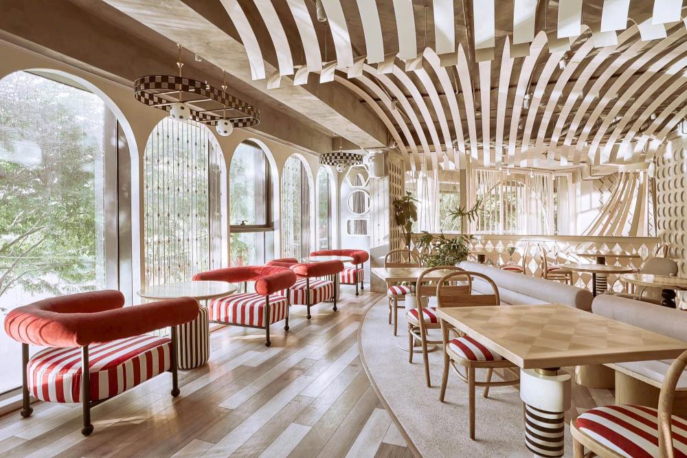 Khám Phá Top 10 Quán Cafe Giảng Võ Hấp Dẫn Nhất Tại Hà Nội 5 Nội thất quán cà phê với bàn ghế gỗ, đệm đỏ kẻ sọc, cửa sổ lớn, và trần nhà thiết kế hình học độc đáo.