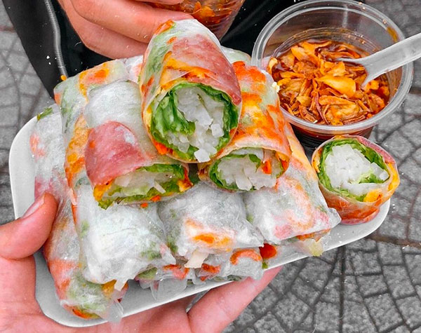 Đĩa gỏi cuốn đầy màu sắc với rau, thịt, bánh tráng, kèm chén nước chấm và hành phi bên cạnh.