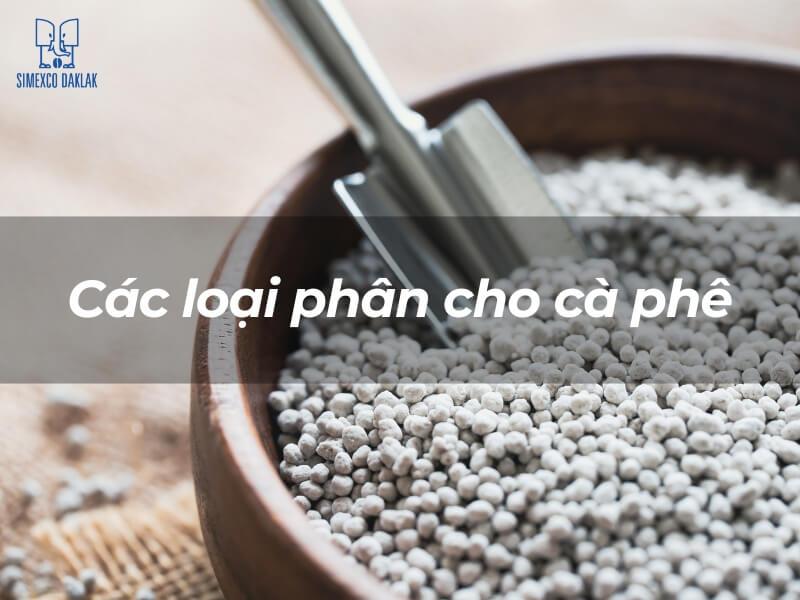 B&aacute;t gỗ đựng ph&acirc;n hạt nhỏ m&agrave;u trắng với c&aacute;i xẻng kim loại b&ecirc;n trong. Văn bản: "C&aacute;c loại ph&acirc;n cho c&agrave; ph&ecirc;".