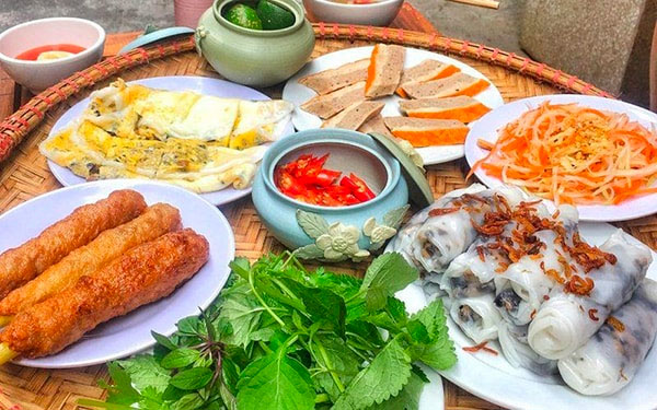 Mâm đồ ăn Việt Nam gồm bánh cuốn, nem rán, giò lụa, rau sống và nước chấm, bày trên mẹt tre.
