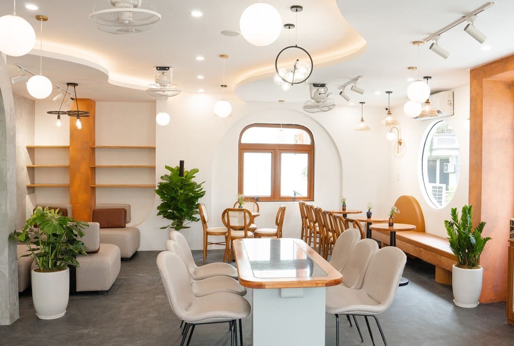 Khám Phá 15 Quán Cafe Hấp Dẫn Trên Đường Nguyễn Thị Định 8 Phòng ăn hiện đại với bàn ghế thoải mái, cây xanh trang trí và ánh sáng tự nhiên từ cửa sổ.