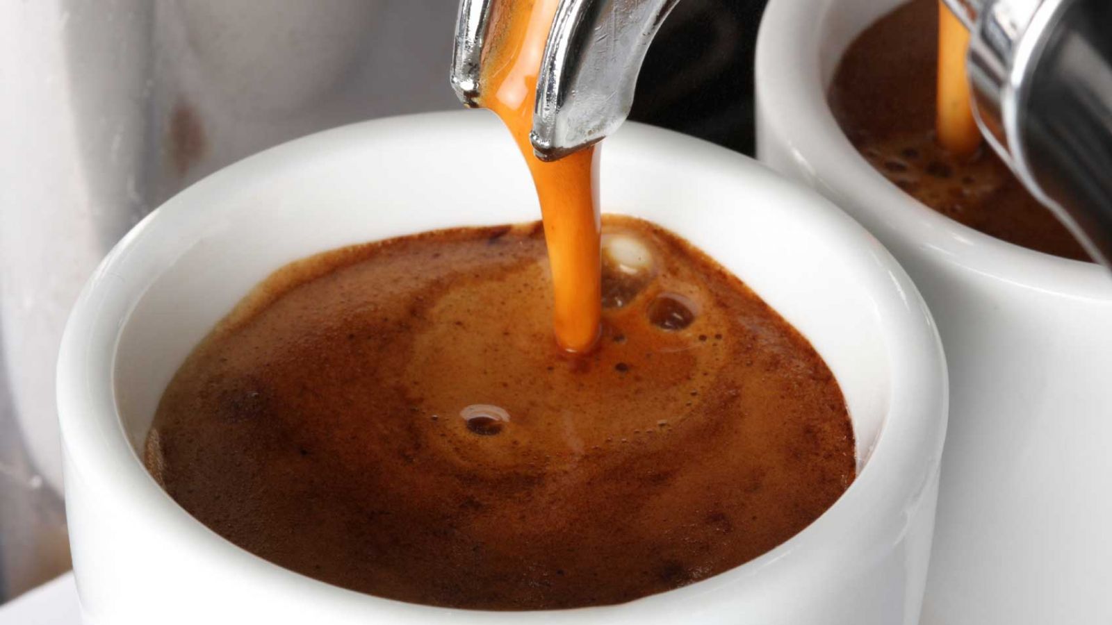 ca-phe-espresso Cận cảnh cà phê espresso đang được rót vào tách trắng, bề mặt có lớp bọt nâu.