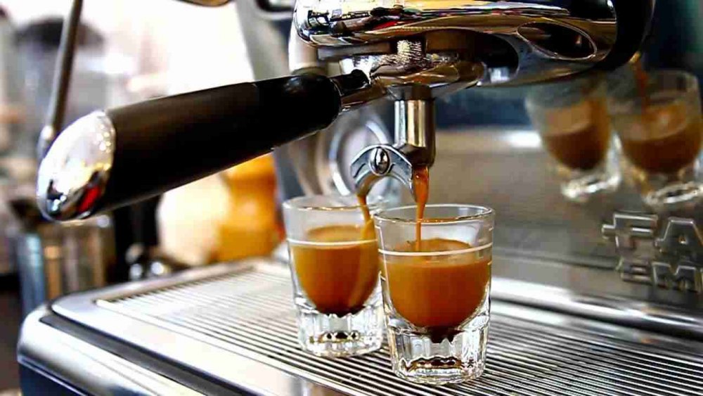 ca-phe-pha-may-la-gi Máy pha cà phê espresso đang rót cà phê vào hai ly thủy tinh nhỏ trên khay kim loại.