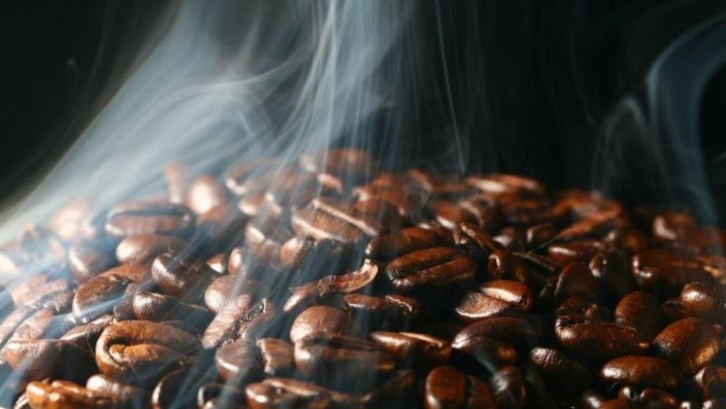 Hạt cà phê nâu bóng với khói bốc lên, tạo cảm giác ấm áp và thơm ngon.