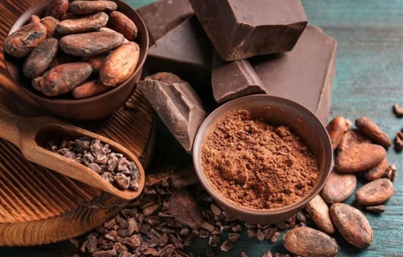 Cận cảnh hạt cacao, bột cacao v&agrave; s&ocirc;-c&ocirc;-la đen tr&ecirc;n b&agrave;n gỗ.