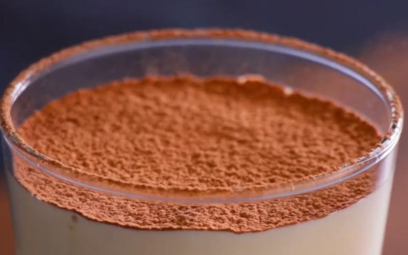 Cốc tr&aacute;ng miệng với lớp bột cacao phủ tr&ecirc;n bề mặt mịn m&agrave;ng, &aacute;nh s&aacute;ng chiếu từ ph&iacute;a tr&ecirc;n, nền tối.