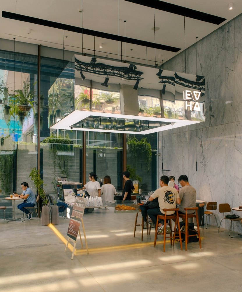 Quán cà phê hiện đại với khách ngồi uống nước, nội thất sáng và rộng rãi, có chậu cây trang trí.