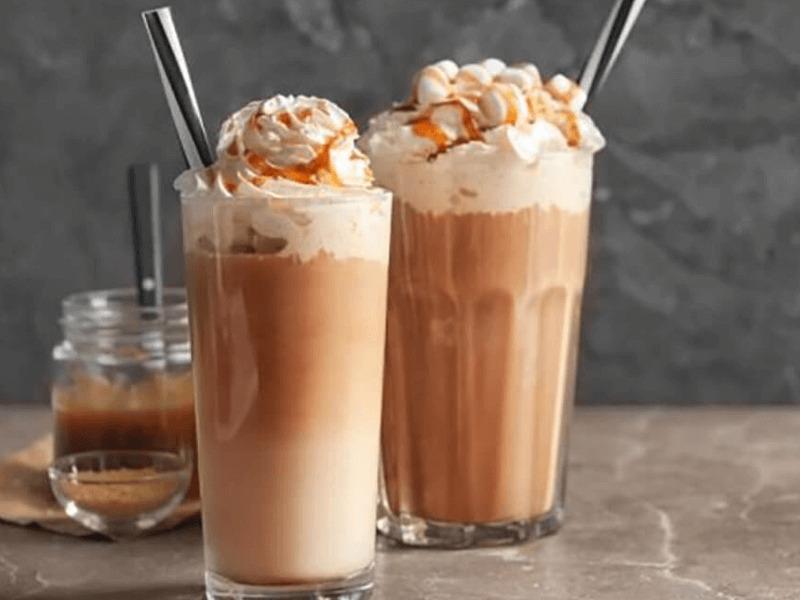 Hai ly cà phê đá xay với kem tươi và sốt caramel, đặt trên bàn đá cẩm thạch.