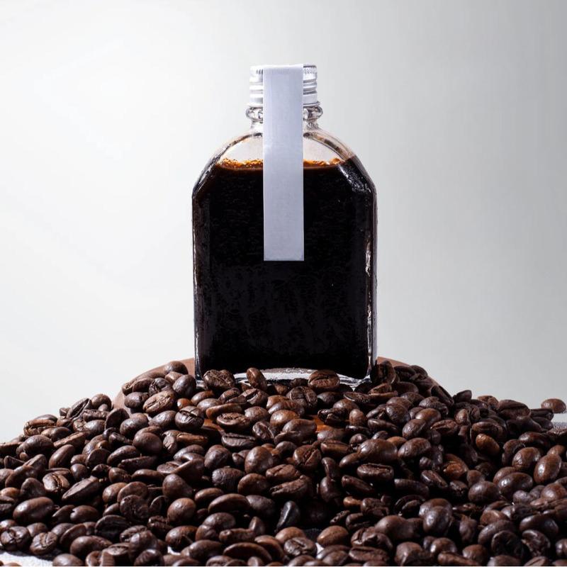 cach-pha-ca-phe-dong-chai-6 Chai thủy tinh chứa chất lỏng màu nâu đậm, đặt trên nền hạt cà phê rang.