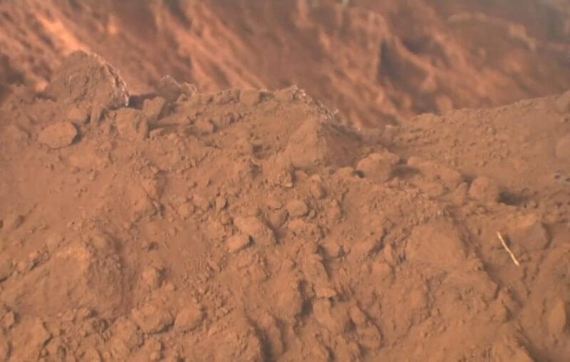 Đất sét màu nâu đỏ với bề mặt gồ ghề và nhiều khối đá nhỏ nằm chồng lên nhau.