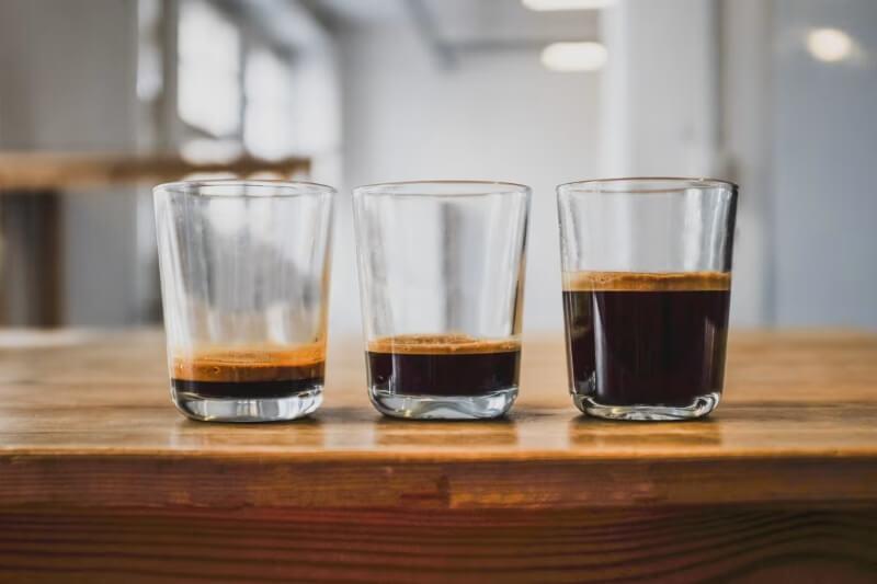 Ba ly c&agrave; ph&ecirc; espresso tr&ecirc;n b&agrave;n gỗ trong kh&ocirc;ng gian nội thất s&aacute;ng.