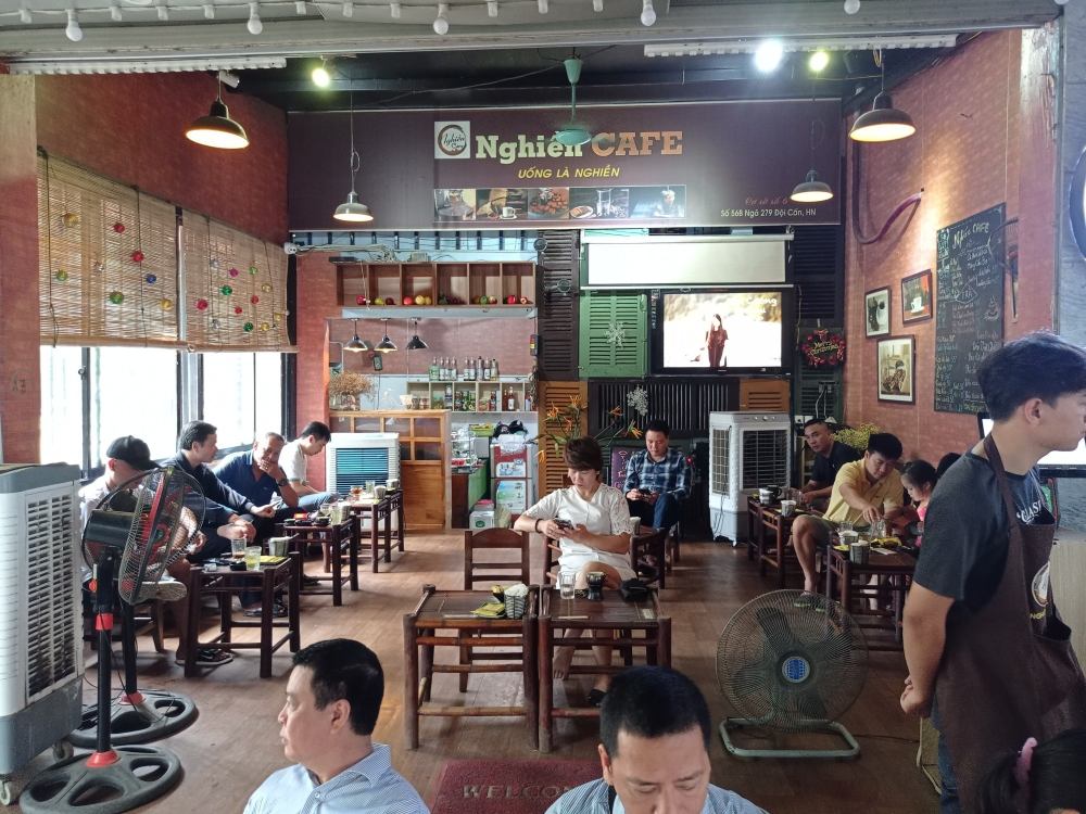 Khám Phá 11 Quán Cafe Đội Cấn Tuyệt Vời Cho Thư Giãn Và Làm Việc 24 Một quán cà phê với khách hàng ngồi trò chuyện và thưởng thức đồ uống, không gian ấm cúng và trang trí đơn giản.