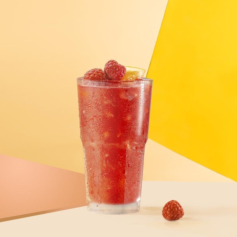 Ly nước m&agrave;u đỏ c&oacute; đ&aacute;, trang tr&iacute; quả m&acirc;m x&ocirc;i v&agrave; l&aacute;t cam, nền v&agrave;ng cam.