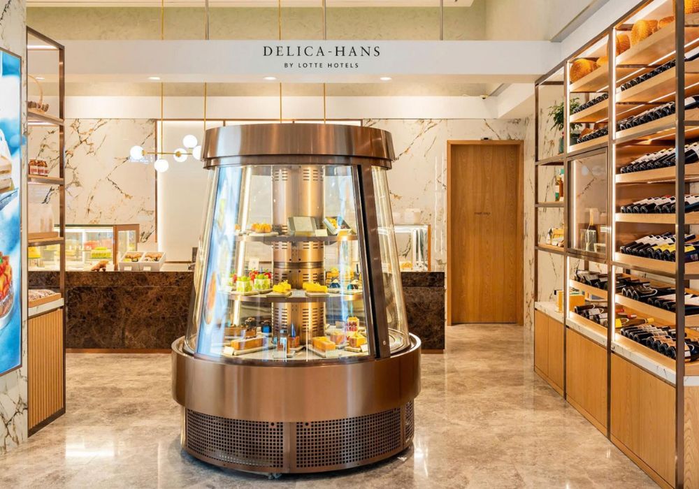 Khám Phá Top Quán Cafe Đẹp Ở Liễu Giai: Đồ Uống Ngon, Không Gian Thư Giãn 23 Quầy trưng bày bánh ngọt trong tiệm, bên cạnh là kệ đựng chai rượu và cửa gỗ.